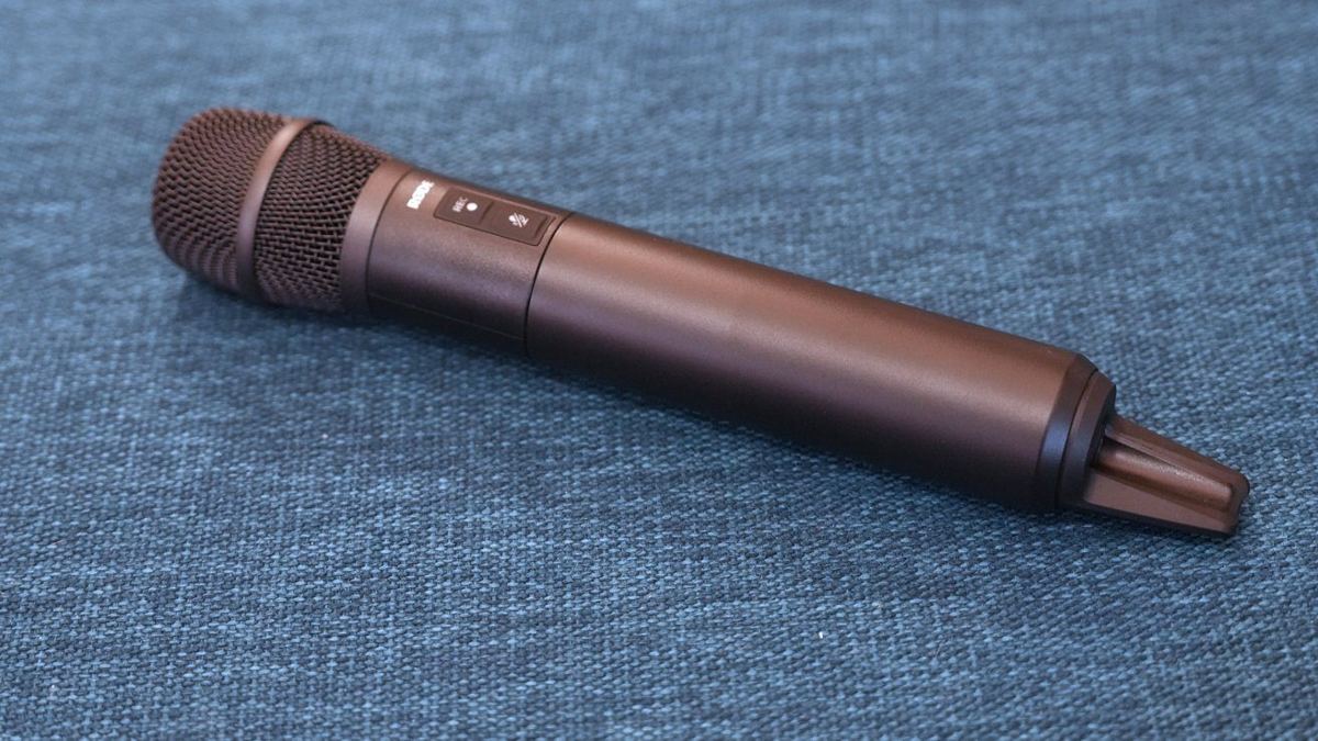Black handheld microphone resting on a textured blue surface.