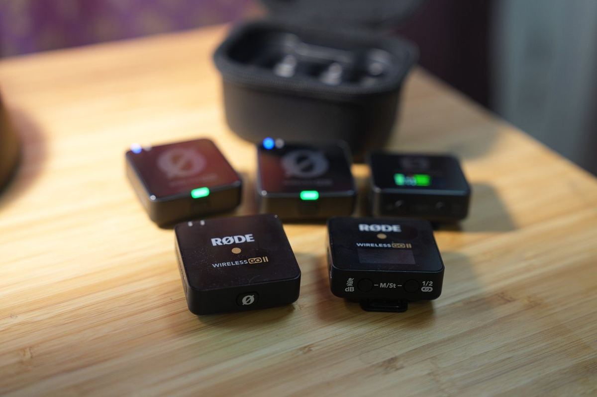 Rode Wireless GO II microphone transmitters on a wooden surface with storage case in the background.